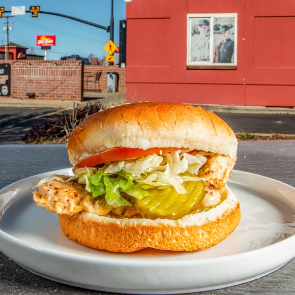 C & B Famous Chicken sandwich with grilled chicken, lettuce, tomato, and pickles on a bun.