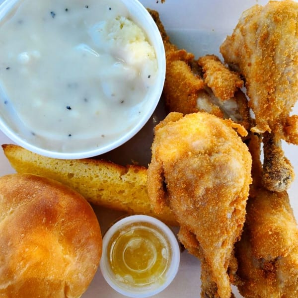 C & B Famous Chicken meal with fried chicken, mashed potatoes and gravy, cornbread, and honey.