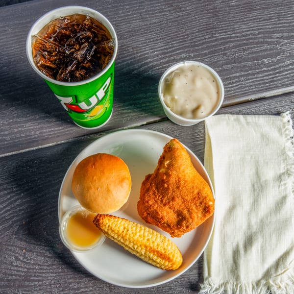 C & B Famous Chicken meal with fried chicken, corn on the cob, roll, gravy, and soda.