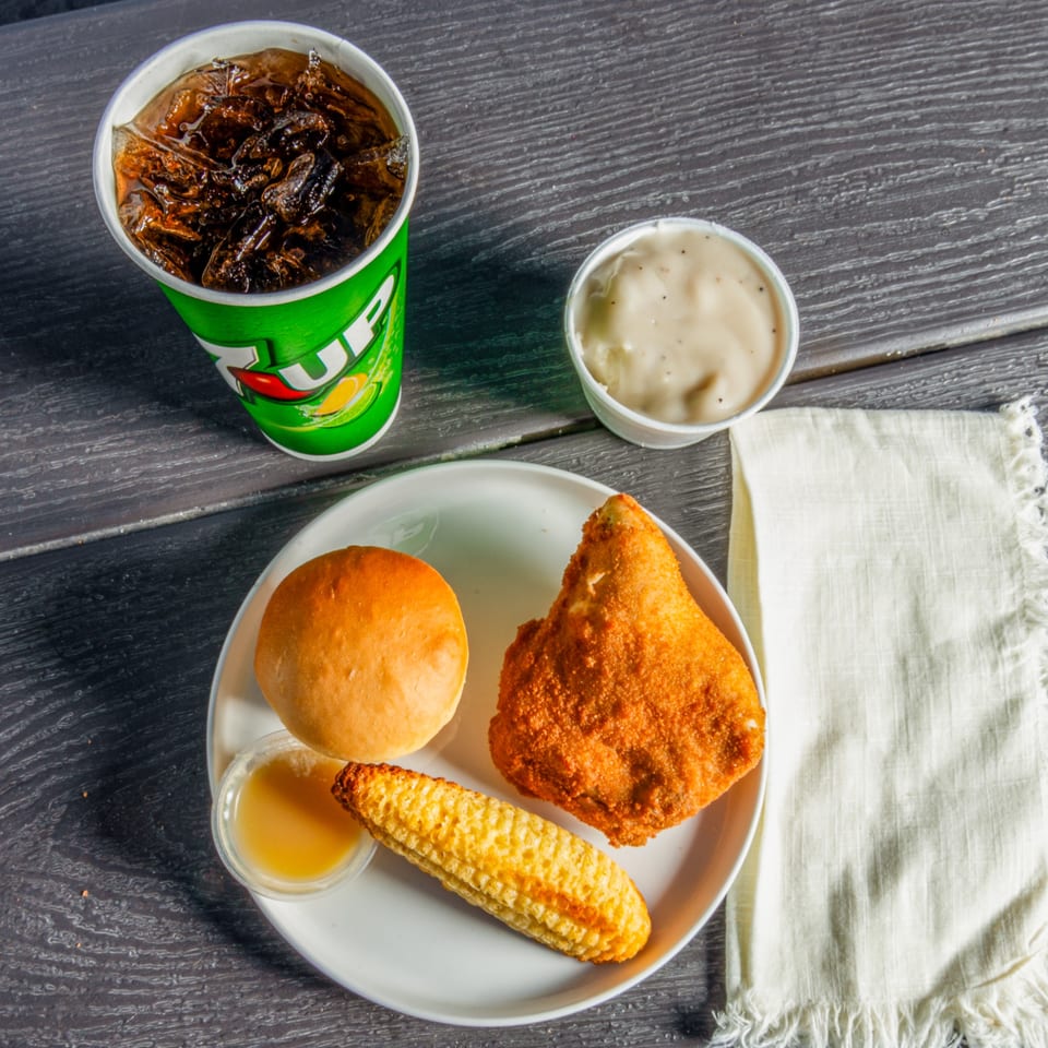 C & B Famous Chicken meal with fried chicken, corn on the cob, roll, gravy, and soda.