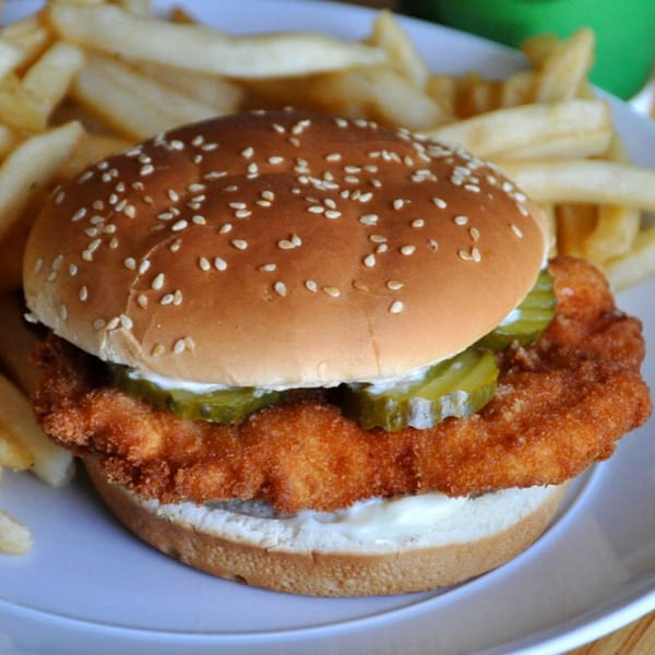 C & B Famous Chicken sandwich with a crispy fried chicken patty, pickles, and mayonnaise, served with fries.